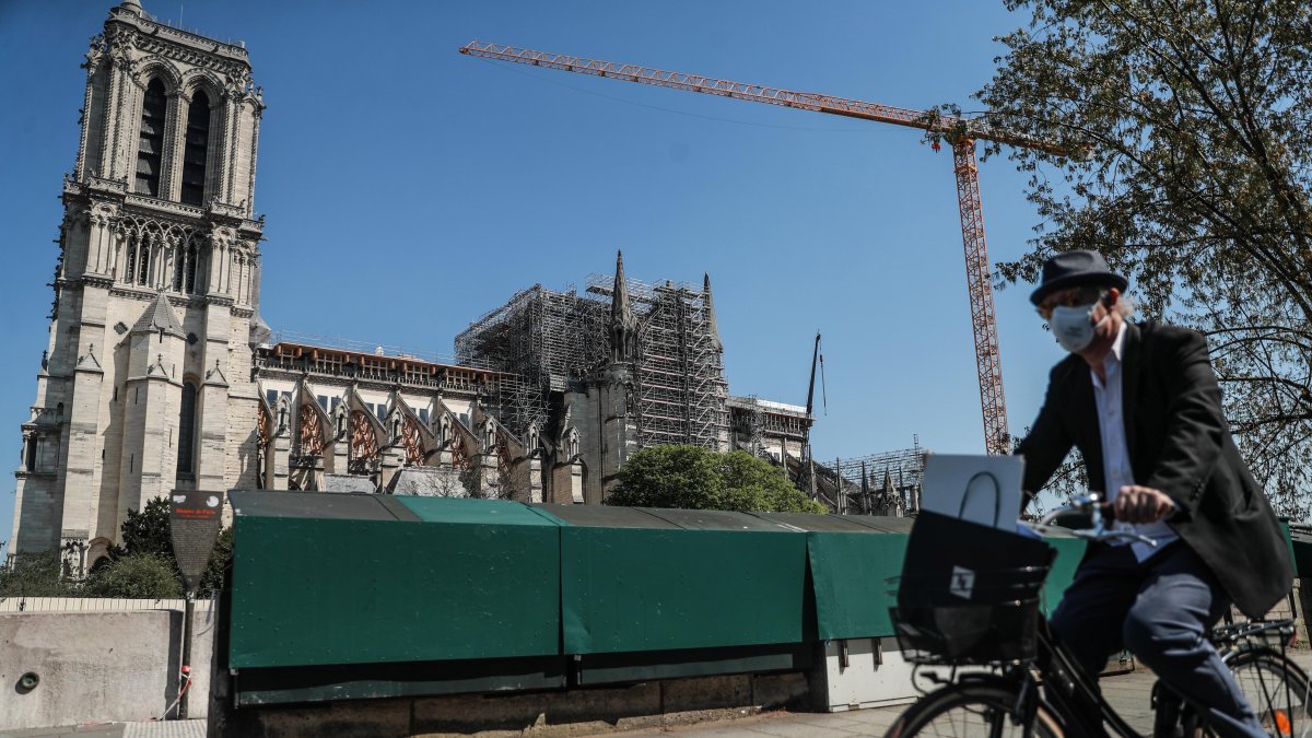 Un hombre que lleva una máscara facial protectora monta su bicicleta junto a la Catedral de Notre Dame, en París