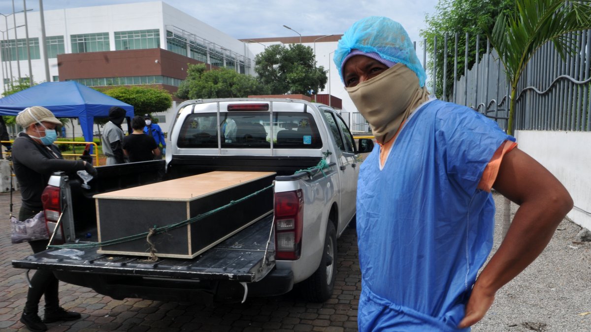 Un hombre se pone un traje protector fuera de la morgue del Hospital General Guasmo Sur para identificar a su pariente que murió del coronavirus.