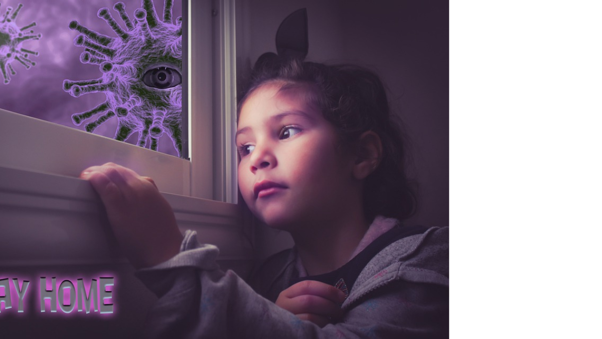 Una niña observa con melancolía desde la ventande su casa.