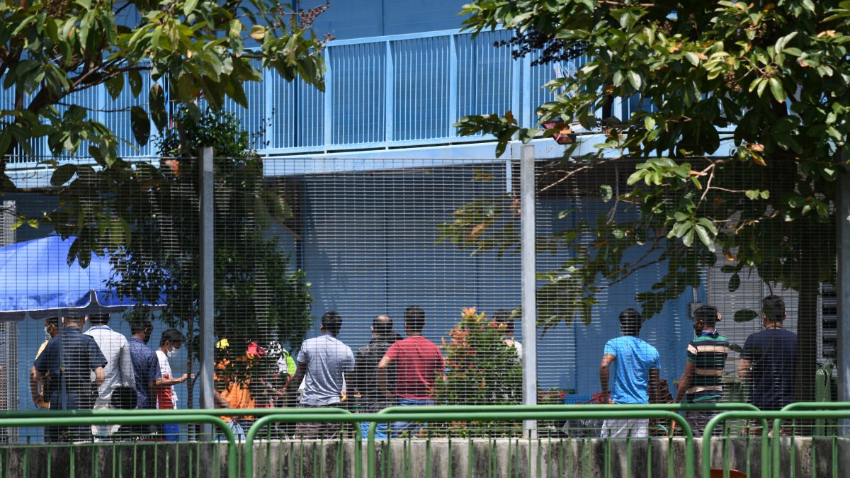 Residentes hacen cola para obtener su comida en el dormitorio de trabajadores extranjeros de Tuas South que se ha puesto bajo restricción gubernamental como medida preventiva contra el COVID-19