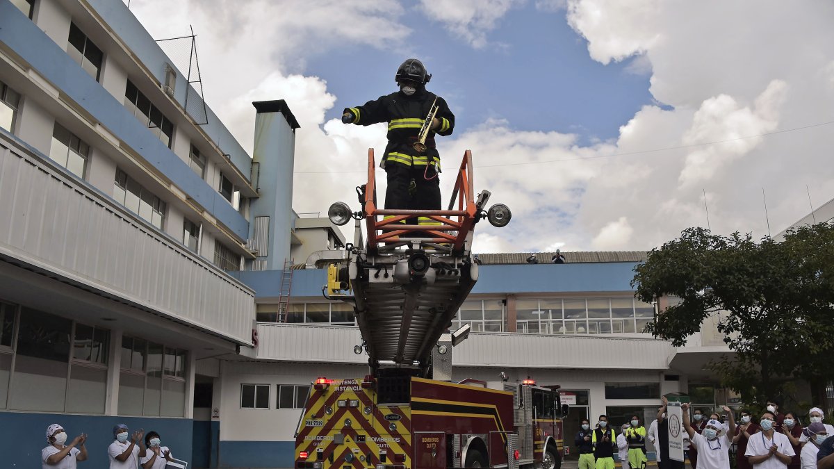 Médicos, enfermeras y auxiliares elevan la mirada para ver el espectáculo musical por parte del grupo de bomberos de Quito.