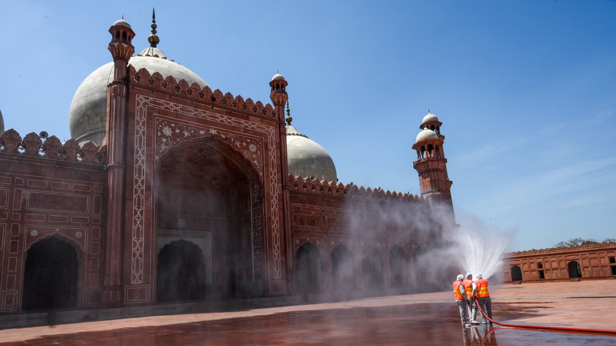 LAHORE. Trabakjadores municipales, se encargan de la limpieza de la  plazoleta aledaña a la mezquita de esta ciudad paquistaní.