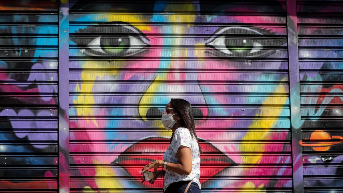 Una mujer con tapabocas es vista en Sao Paulo. Funcionarios desinfectan las calles de Paraisopolis, una de las mayores favelas de la ciudad.