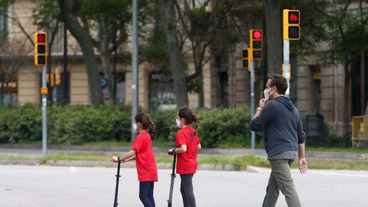 Un hombre y sus dos hijas caminan por una calle de Barcelona este lunes, segundo día en el que los menores de 14 años pueden salir a la calle una hora tras una cuarentena de 44 días.