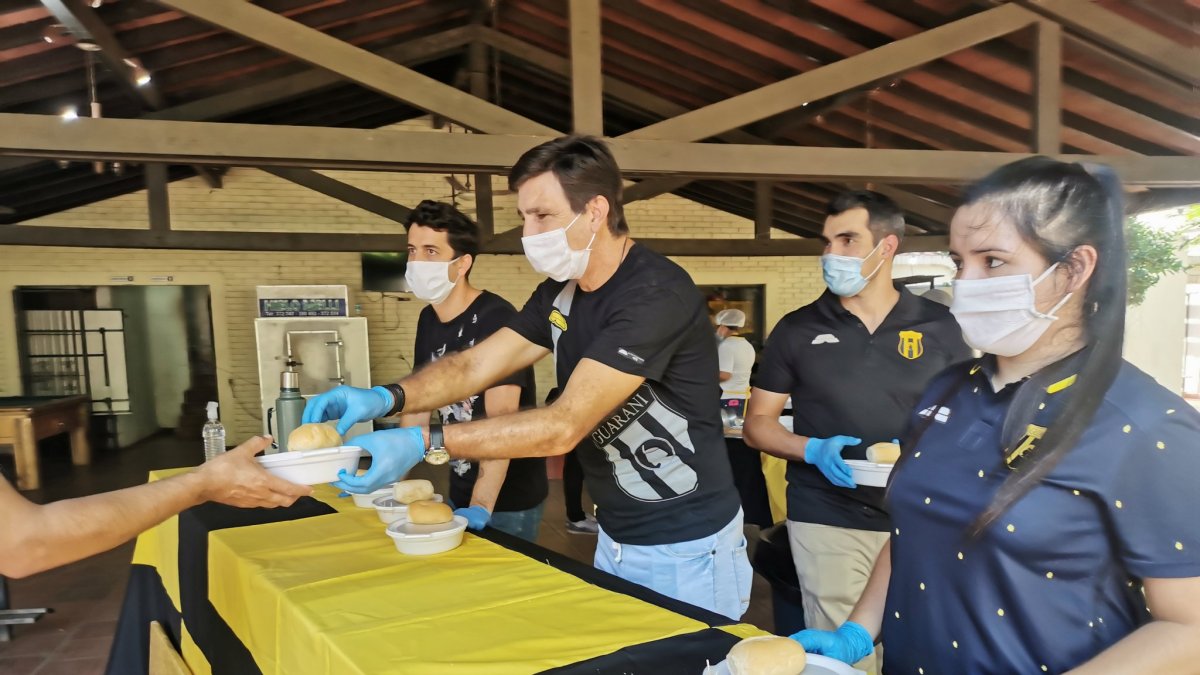 El técnico Gustavo Costas (c) durante la entrega de un guiso de arroz con pollo como parte de la iniciativa olla popular.