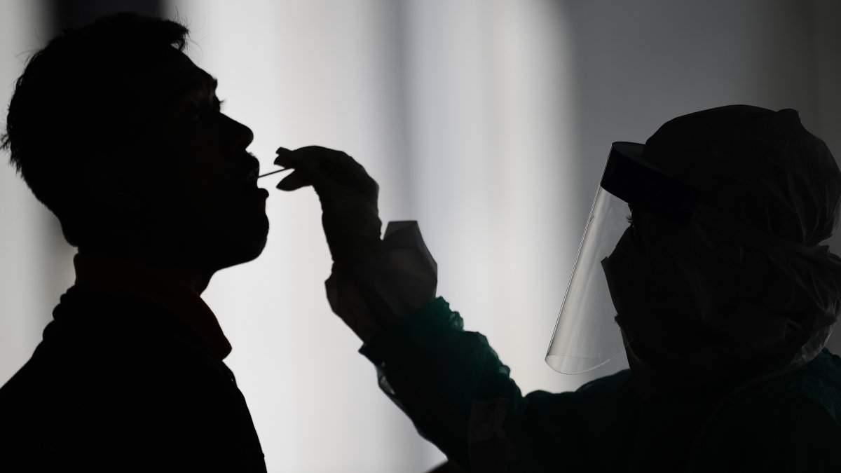 Un trabajador de salud usa un hisopo para recolectar una muestra para la prueba de coronavirus COVID-19 de un hombre en Gombak, Kuala Lumpur