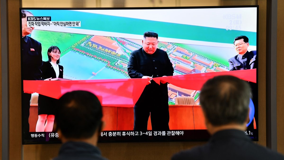 La gente mira una pantalla de televisión que muestra una imagen del líder norcoreano Kim Jong -un asistiendo a la inauguración de la fábrica de fertilizantes fosfáticos Sunchon