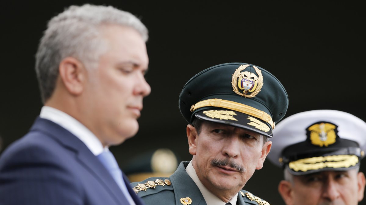 El saliente comandante del Ejército de Colombia, general Nicacio Martínez (c) y el presidente Iván Duque (i) durante una ceremonia militar de diciembre del año pasado