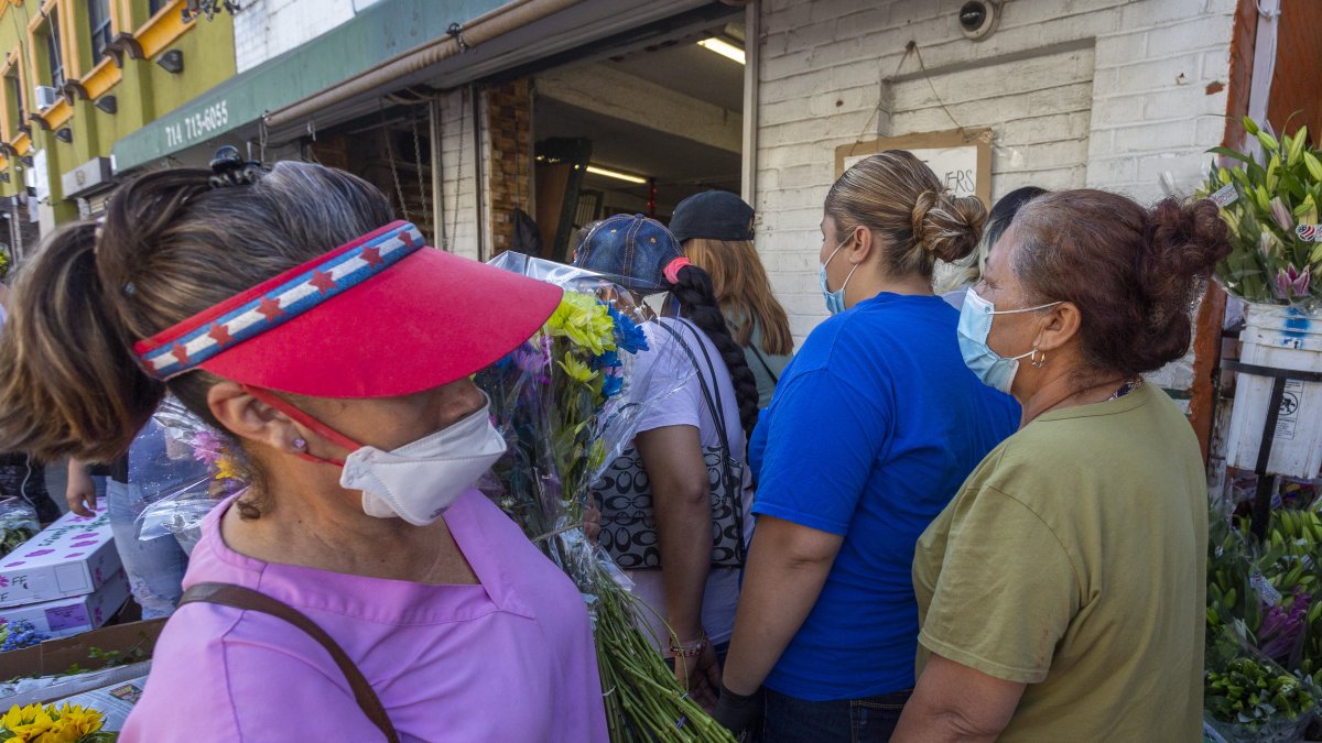 Ciudadanos se mezclan entre sí, irrespetando el distanciamiento obligatorio por la pandemia, en un mercado de flores de California