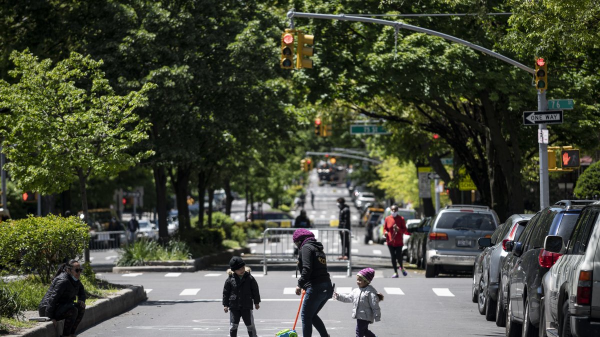 Los síntomas se presentan entre los 5 y 21 años, según las autoridades.En la gráfica,  una mujer juega con dos niños en una calle cerrada al tráfico vehicular en el distrito de Queens