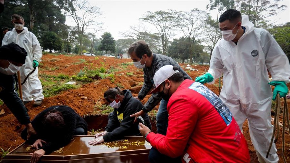 James Ala, coordinador de sepultureros, observa una familia desconsolada durante el entierro de un ser querido en el cementerio Vila Formosa, en Sao Paulo (Brasil).