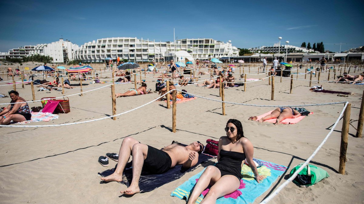 LA GRANDE MOTTE (Francia). Dos personas toman el sol en una playa en el sur de Francia. El municipio local es el primero en implementar zonas separadas para respetar el distanciamiento social.