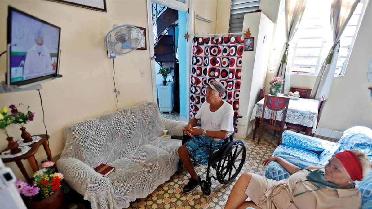 La pareja de sexagenarios Inés d y Egaldo observan en la televisión la habitual conferencia del Ministerio de Salud Pública este viernes, en La Habana (Cuba).