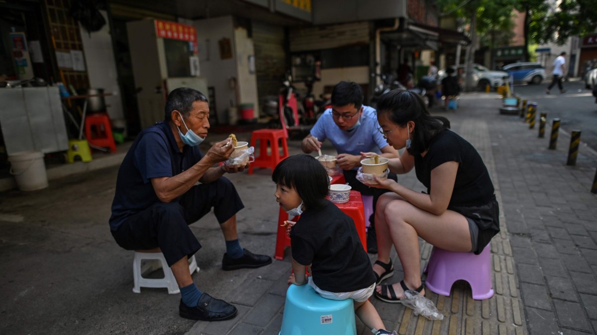 WUHAN. Una familia come en grupo y al aire libre en un restaurante callejero. Esta ciudad china vive ya varios días de una fase de pospandemia.