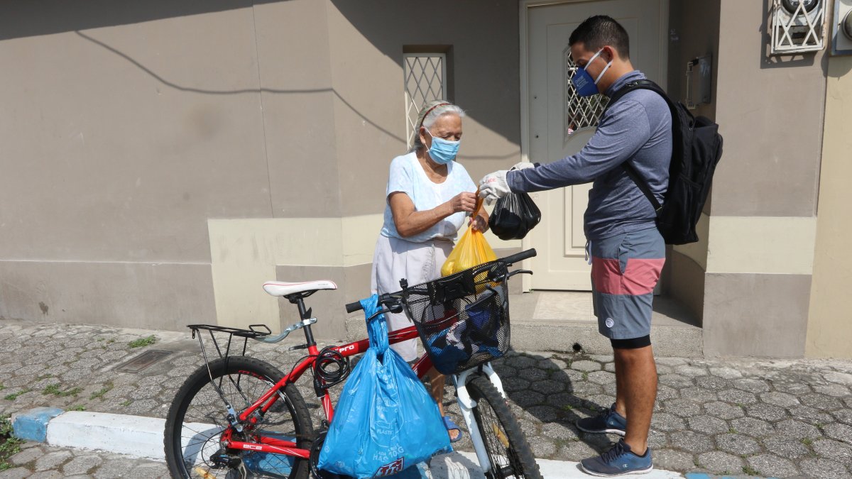 Enrique Bravo entrega el mandado a una de sus vecinas de la tercera edad, en Samanes. Él, para movilizarse, utiliza una bicicleta, así puede salir a ayudar todos los días.