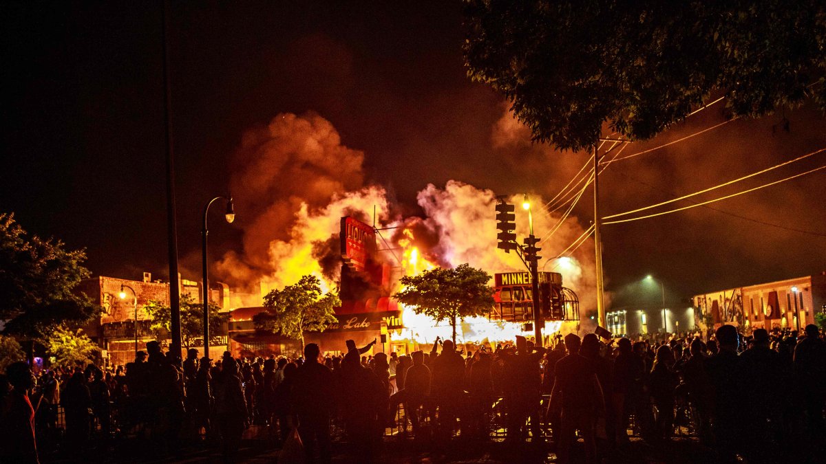 MINÉAPOLIS. Los manifestantes se reúnen alrededor de una licorería en llamas cerca del Tercer Recinto Policial.