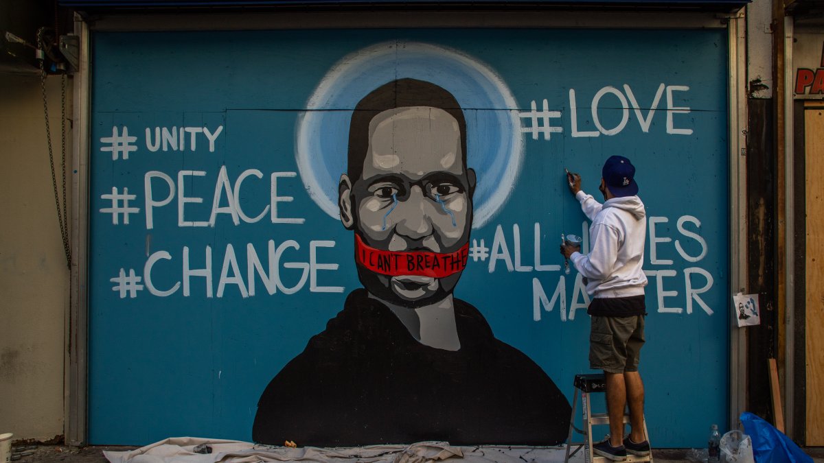 En el centro de  Los Ángeles, un artista pinta un mural con el rostro de George Floyd, el hombre negro que murió mientras era arrestado 