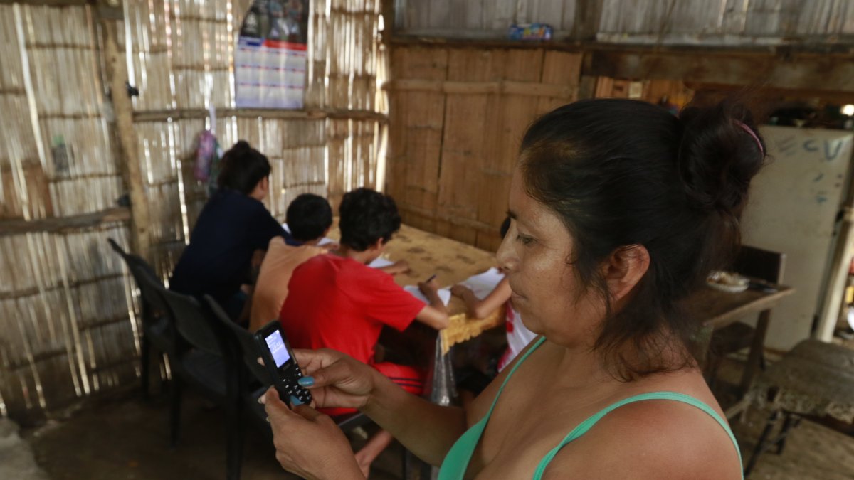 A través de un teléfono celular vetusto, esta madre trata de comunicarse con los maestros de sus hijos. En su casa no hay computador.