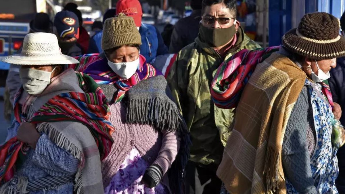 Personas que llevan máscaras faciales caminan por las calles de El Alto mientras Bolivia busca reactivar la economía en medio de la nueva pandemia de coronavirus.