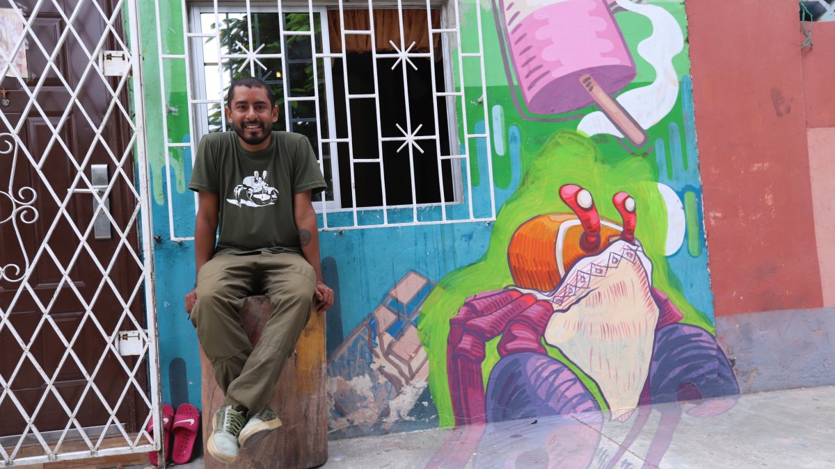 Gabriel Peña, muralista guayaquileño, posando en una de sus pinturas en su sector.