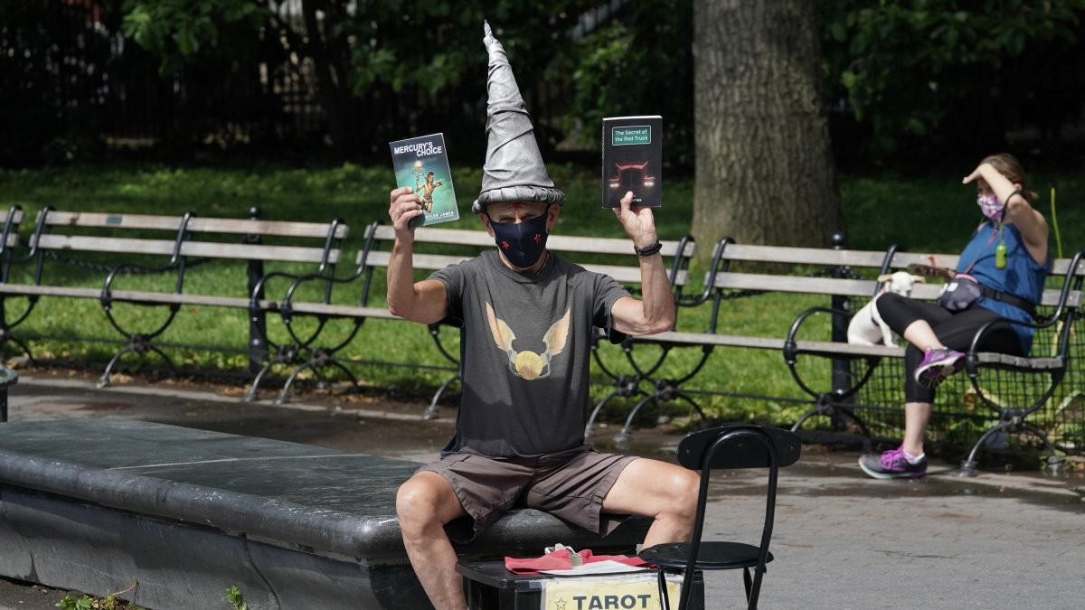 El mago de los juegos y las cartas del tarot, Kyler James, se sienta en el Washington Square Park de Nueva York el 9 de junio de 2020. ¿Cuándo podría haber una vacuna?