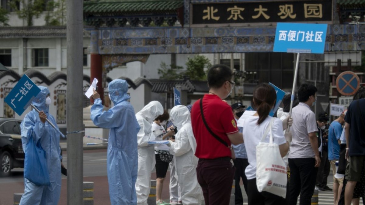 Miembros del personal sanitario sostienen carteles con indicaciones en el mercado de Xinfadi.