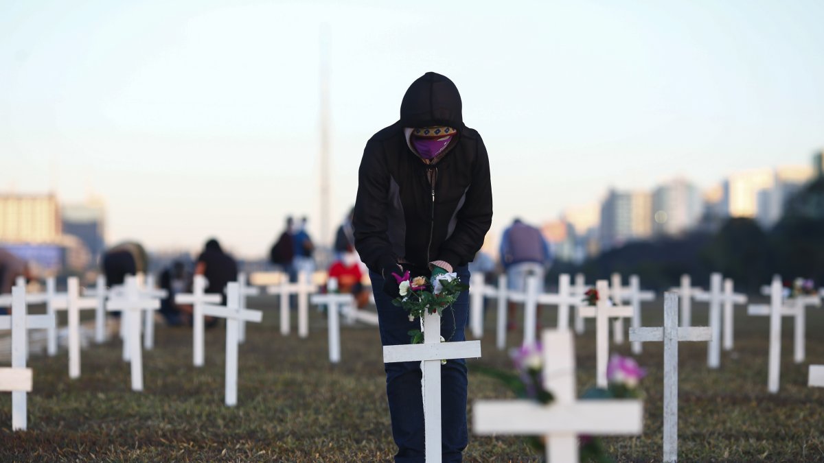 Un manifestante coloca flores en una cruz durante una protesta contra el presidente brasileño Jair Bolsonaro y en honor a las personas que murieron por COVID-19 