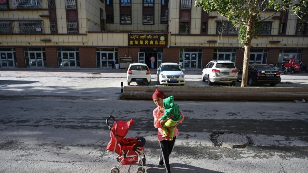 Una mujer pasea con un bebé por el barrio uigur de la ciudad china de Aksu, en la región de Xinjiang, en de septiembre de 2019-