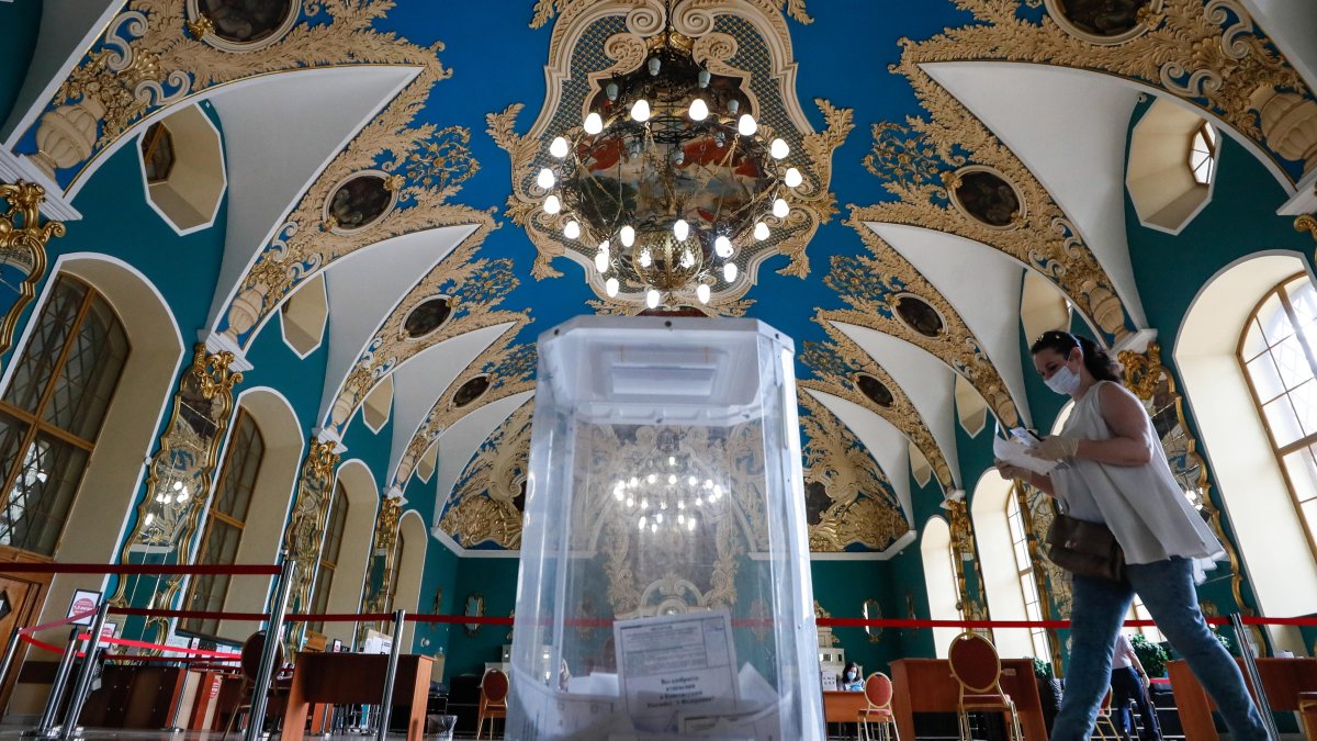 MOSCÚ. Un votante,con máscara facial y guantes, camina hacia una urna para emitir su voto en un colegio electoral de la estación de ferrocarril de Kazansky.