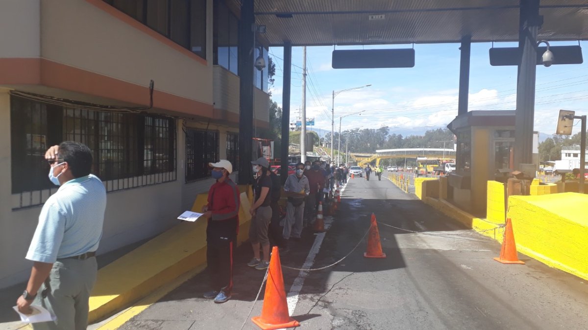 Usuarios esperan encolumnados por un turno de atención en el sector del peaje de la Autopista General Rumiñahui, de Quito.