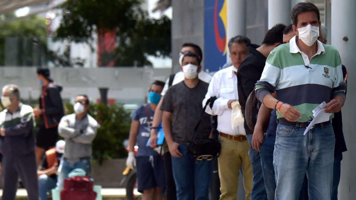 Un grupo de hombres hace fila para entrar a un banco en Bogotá, Colombia.