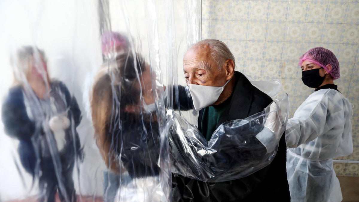 SAO PAULO. María Paula Moraes saluda a su padre de 82 años, que vive en una residencia de ancianos, a través de una 'cortina de abrazos', una alternativa en medio del distanciamiento social.