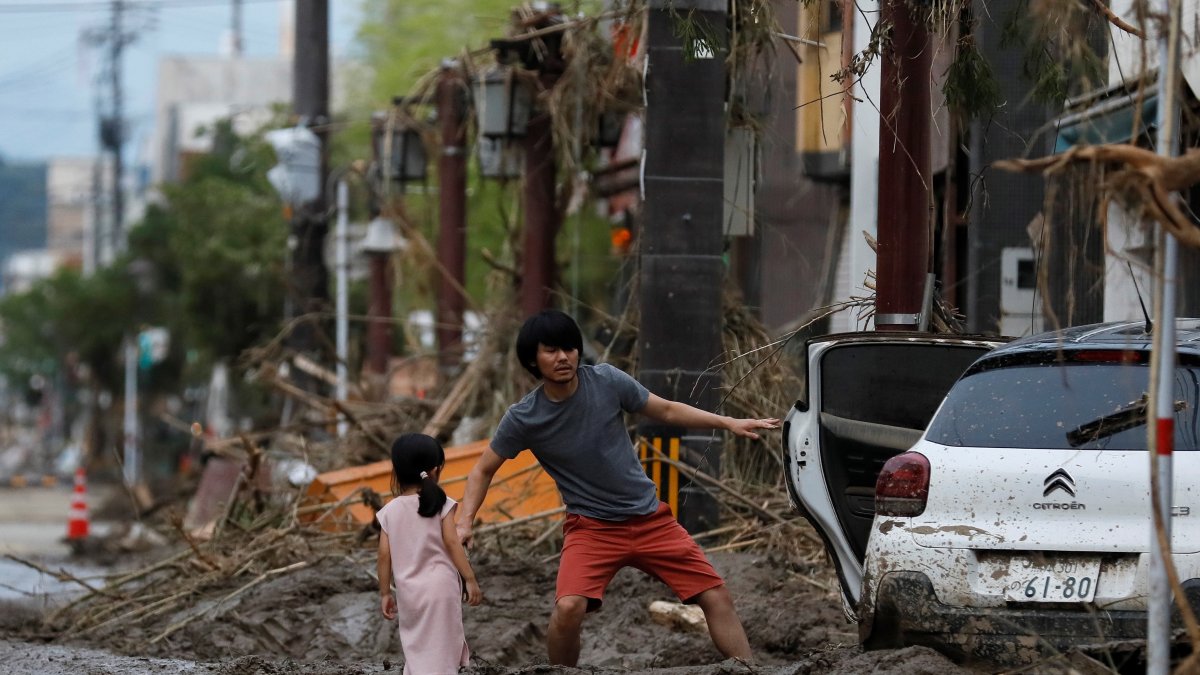Una niña observa a su padre mientras recupera algunas de sus pertenencias tras las fuertes lluvias de este miércoles en Kurume (Japón). 