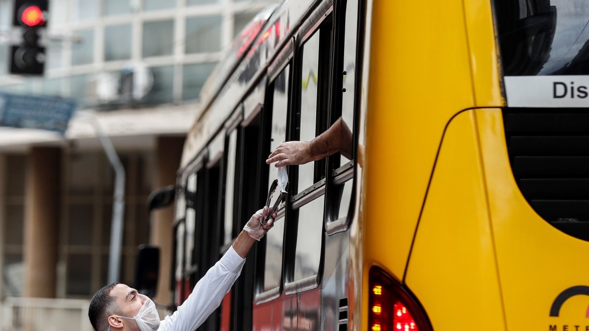 Voluntarios entregan mascarillas, en el centro de Sao Paulo, Brasil, durante una operación de Vigilancia Sanitaria para fiscalizar y advertir sobre su uso obligatorio para prevenir el COVID-19 