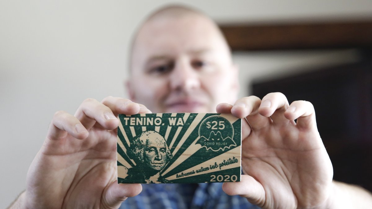 El alcalde de Tenino, Wayne Fournier, muestra el billete de madera de 25 dólares.