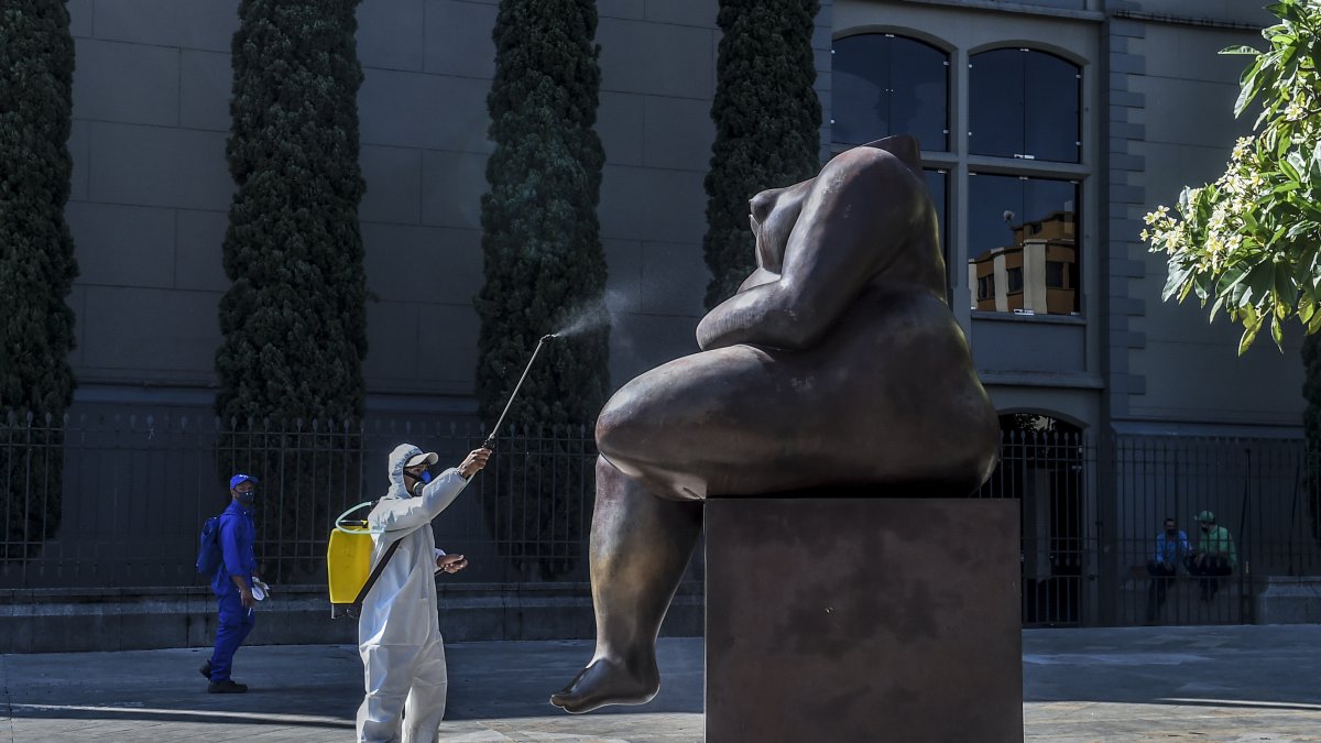 Un trabajador desinfecta una estatua de los artistas colombianos Fernando Botero, en Medellín, en medio de la pandemia de Covid-19