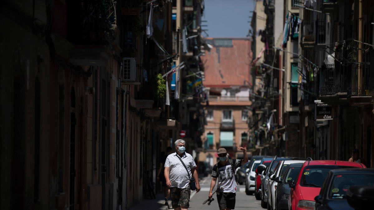 BARCELONA. Dos personas transitan por una calle, ayer, tras el pedido de las autoridades de no salir de casa.