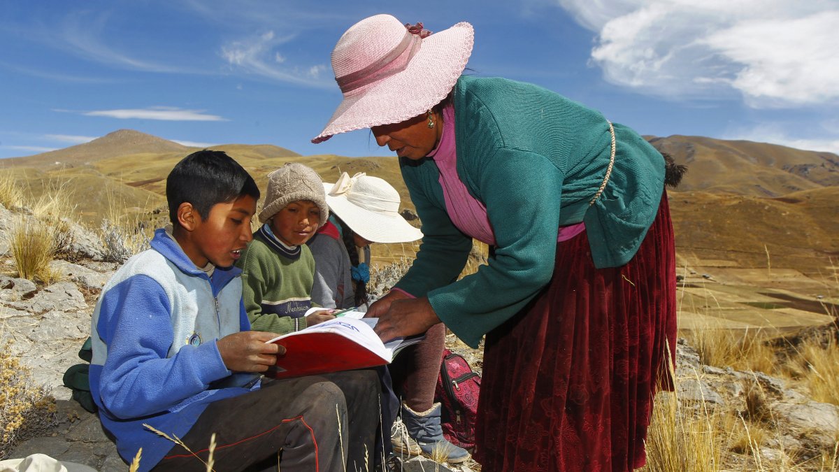 Raymunda Charca junto a sus  hijos en la cima de una colina, donde pueden recoger la señal en sus teléfonos móviles para recibir clases virtuales. 