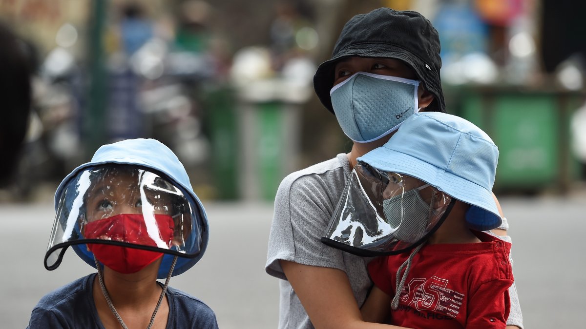 Una mujer espera con sus hijos en un improvisado centro de pruebas rápidas, este viernes en Hanoi, Vietnam 