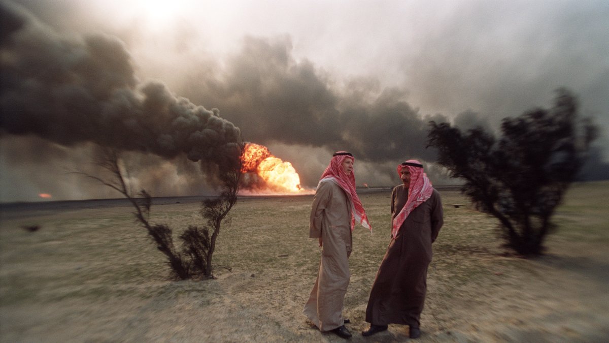 AL-AHMADI. Dos hombres kuwaitíes caminan el 26 de marzo de 1991 por incendiado campo petrolero, tras el retirarse las tropas iraquíes.