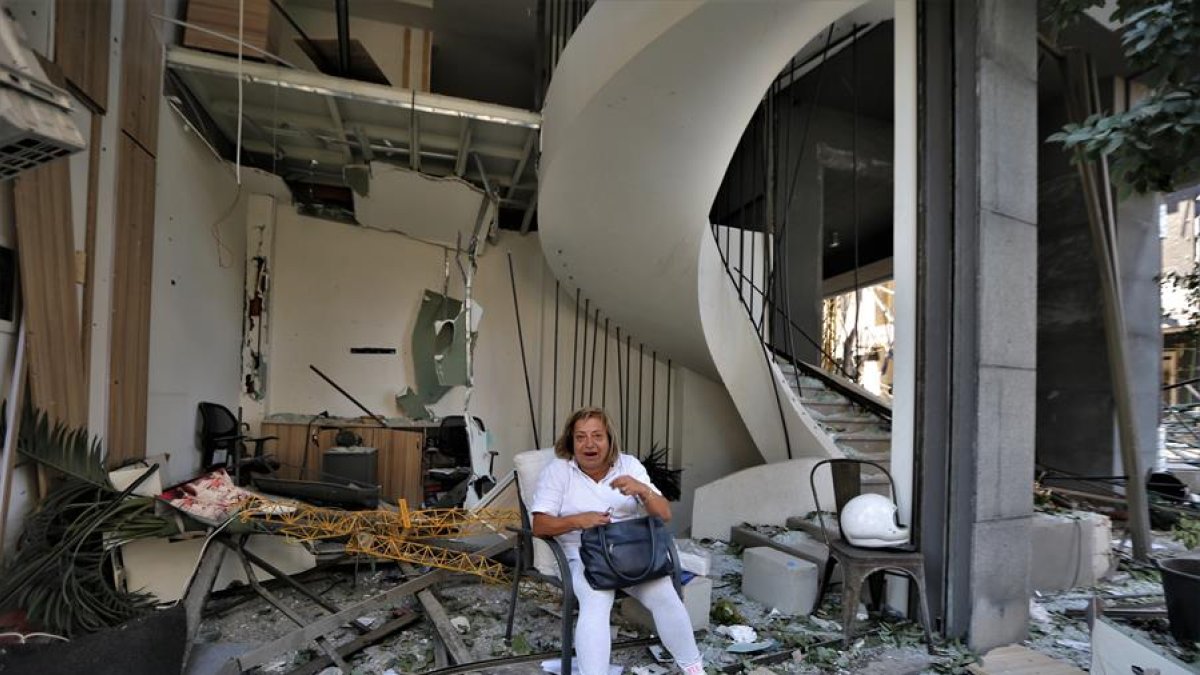 Una mujer se sienta frente a un edificio dañado por la explosión masiva en Beirut, Líbano. Al menos 100 personas murieron y más de 4.000 resultaron heridos.