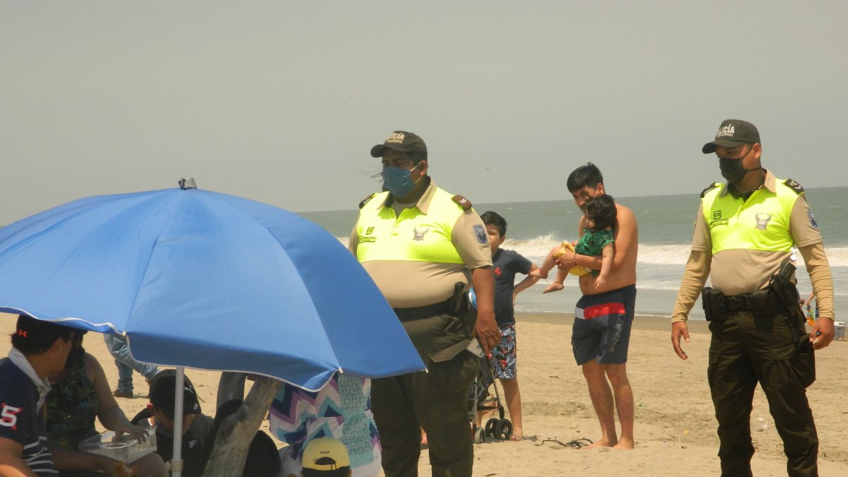 Dos agentes de policía desalojan a unos turistas que disfrutaban del balneario de Playas.