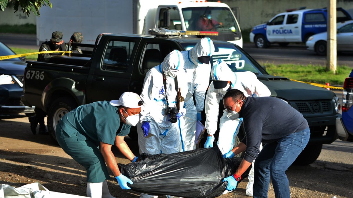 Policías y forenses, el 19 de agosto, recogieron una bolsa de plástico negra que contiene un cadáver en una calle de Tegucigalpa.