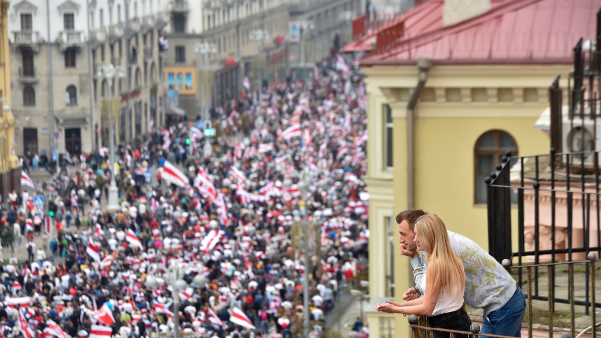 Una pareja mira a los manifestantes desde un balcón durante una marcha de partidarios de la posición en Minsk.