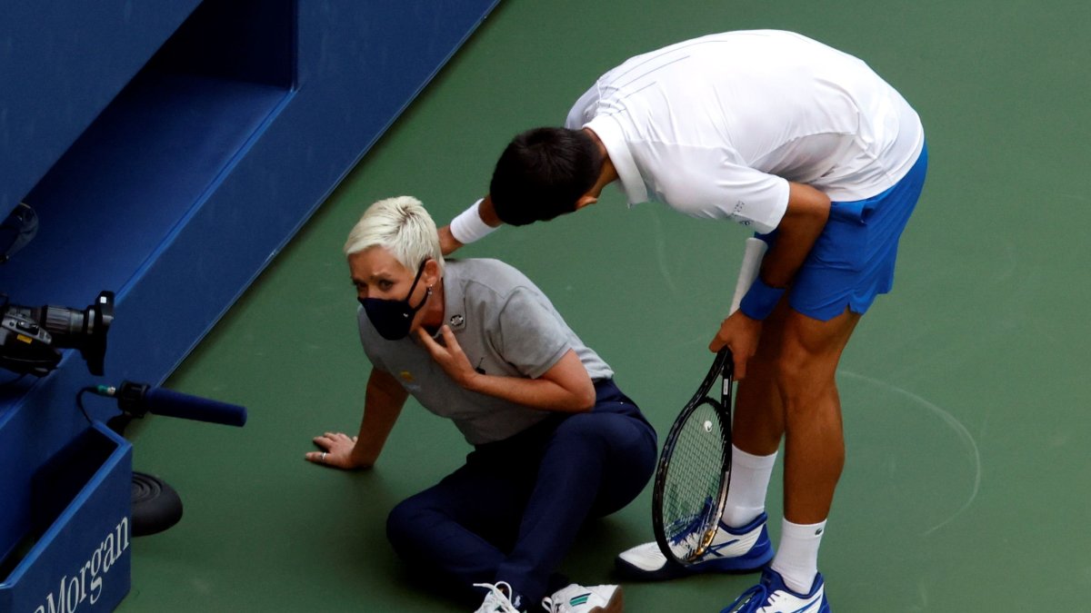 El tenista serbio Novak Djokovic intenta ayudar a una juez de línea después de golpearla con una bola en la garganta.