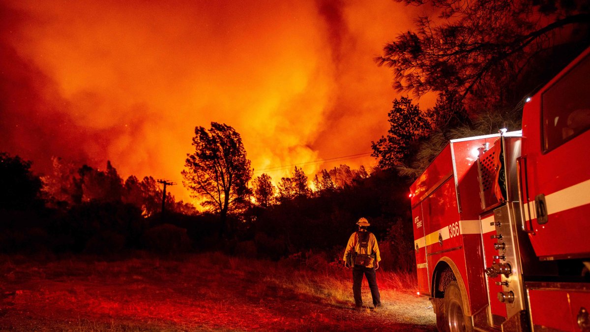 OROVILLE. Un bombero observa impasible cómo las llamas se elevan sobre su camión en el incendio en esta ciudad californiana la noche de este miércoles.