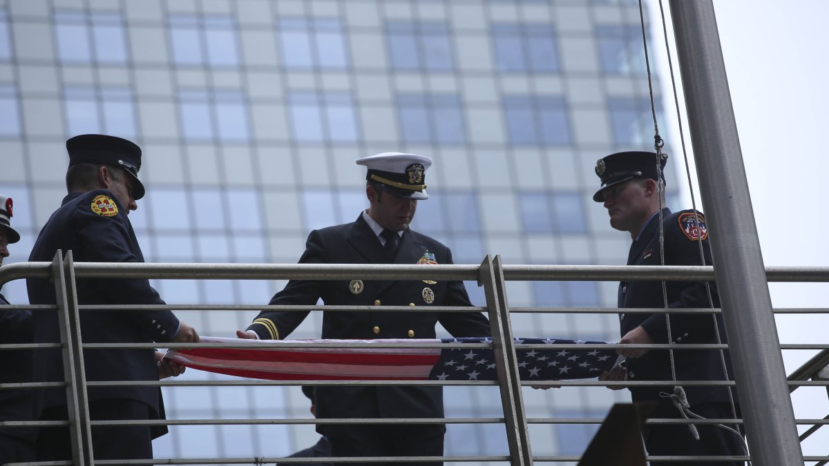 Bomberos de Nueva York se preparan para izar la bandera estadounidense en la conmemoración del año pasado.