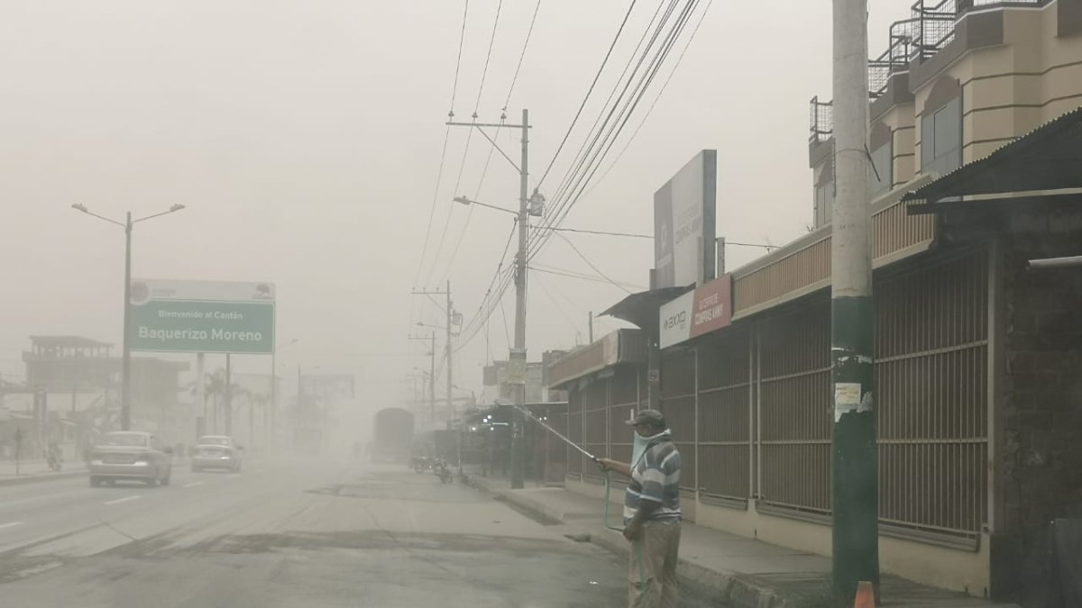 Ciudadanos en el cantón Jujan, del Guayas, esparcen agua en la calzada para evitar la dispersión de la ceniza.