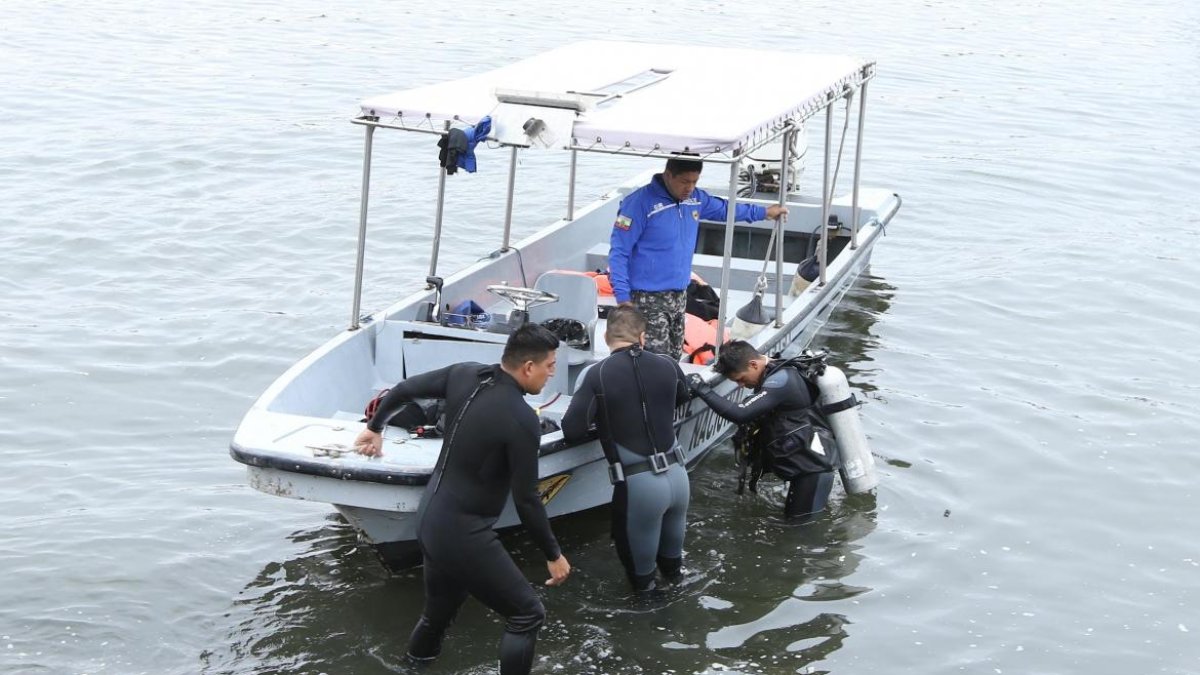 Buzos del Grupo de Intervención y Rescate (GIR), de la Policía Nacional, realizan la búsqueda del muchacho.