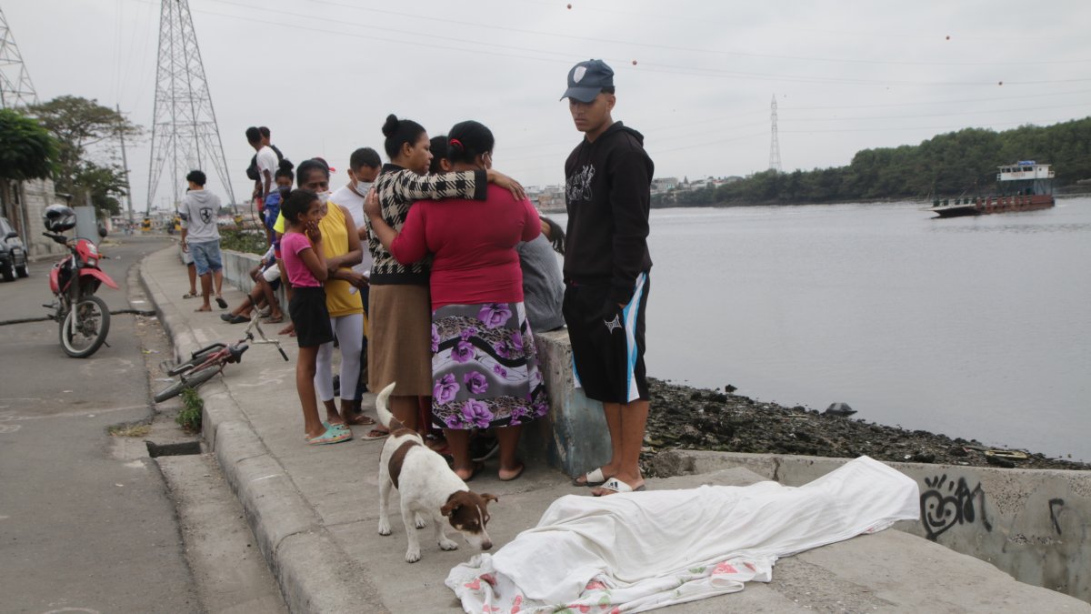 Tobby, mascota de Jordan David Perlaza Velásquez, gime y ladra por la muerte de su amo. Al fondo familiares y vecinos lloran por el suceso.